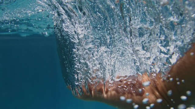 Submerged body movement generates turbulent bubble trails beneath tropical Atlantic water near Pre&aacute;, Cear&aacute;, Brazil, super slow motion underwater action shot with surface distortion.