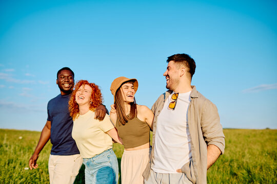 Group of diverse young friends enjoying a cheerful walk together, embracing friendship and happiness outdoors during summer