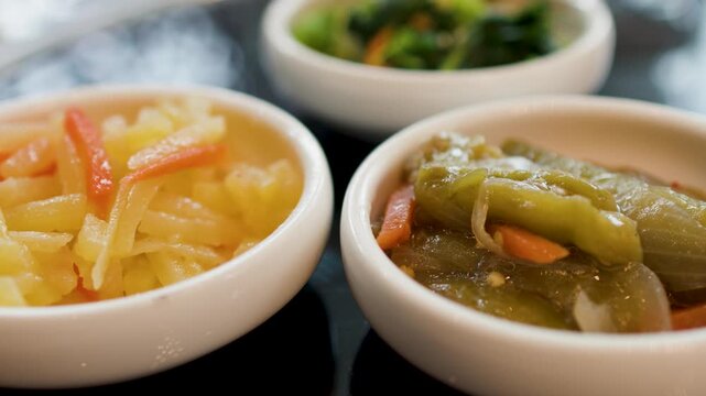 Assorted Korean Banchan Side Dishes Served in Small White Bowls