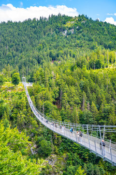 Highline 179 is a suspension bridge in Austria. It connects the ruins of a castle with a Roman fortress. Many people walk across the bridge, enjoying the view of the gorge and forested hills.