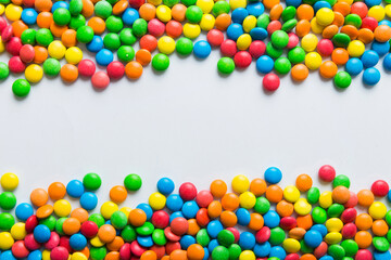 Obraz premium Mixed collection of colorful candy, on colored background. Flat lay, top view. frame of colorful chocolate coated candy