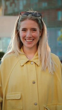Joyful young woman smiling happily while enjoying a sunny day with friends at a lively gathering full of laughter and connection, embodying warmth and positivity in a social atmosphere.