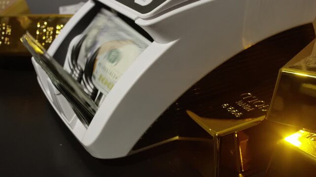 Money counting machine. Dollars in motion. Gold bars and US dollars. Money counting action. Banking operation with money and gold. Business concept with gold bar and money. Counting machine for