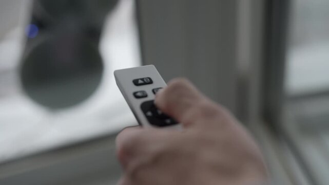 Closeup of male hand holding using remote control to operate modern robotic window cleaner washing glass from outside, innovative solution for domestic chores and home automation technology concept.