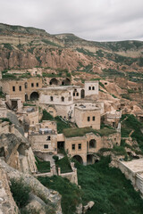 Obraz premium Scenic view of the ancient rock-cut cave houses and stone buildings in the historic village of Cavusin, Cappadocia, Turkey