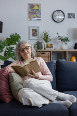 Obraz premium Senior woman relaxing at home reading book