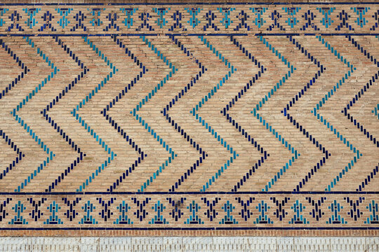 Geometric brickwork with turquoise and blue glazed tiles on the wall of Bibi Khanum Mosque in Samarkand. Ideal for travel publications, heritage documentation, and architectural design references.