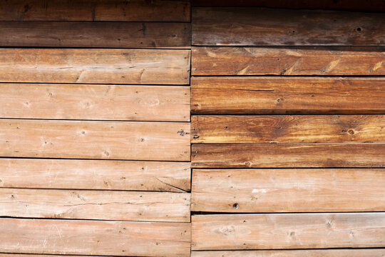 Natural wooden wall background with horizontal planks in two different shades. Rustic timber surface texture for construction design. Vintage brown deck board pattern for interior decor.