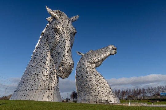 The Kelpies in Falkirk, Scotland, under blue sky, iconic horse head sculptures and famous Scottish landmark at Helix Park.