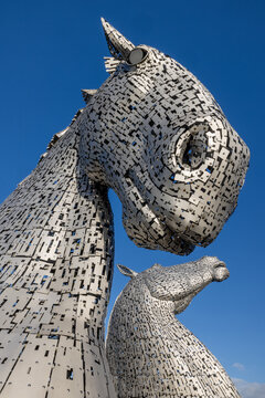 The Kelpies in Falkirk, Scotland, under blue sky, iconic horse head sculptures and famous Scottish landmark at Helix Park.