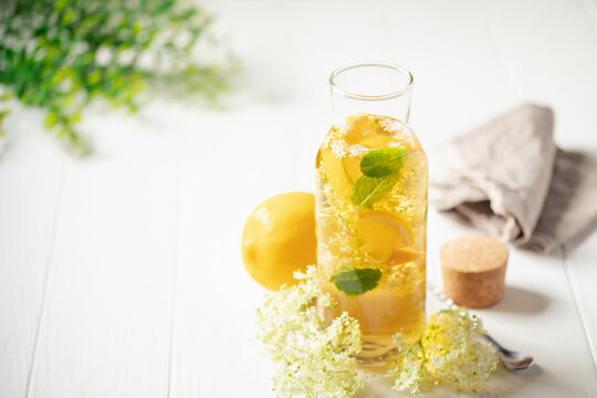 Elderflower syrup in jug, ingredients and accessories visible on the table