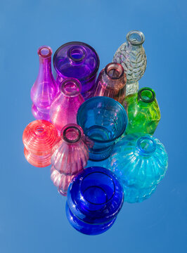 colorful glass vases and bottles on mirror reflecting the blue sky