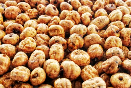 Dried chufa tiger nuts background macro photography heap of wrinkled round yellow brown plant tubers raw healthy organic food ingredient full frame top view close up natural texture layout pattern