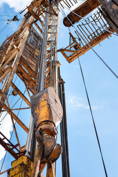 Drilling rig with top drive system (TDS) during tripping in the drill pipe to drill the hole in crude oil exploration operation with sunny blue sky background. Heavy industrial working scene.