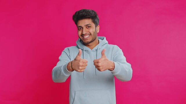 Like. Indian man raises thumbs up agrees with something or gives positive reply recommends advertisement likes good idea feedback, celebrating success victory. Guy isolated on studio pink background