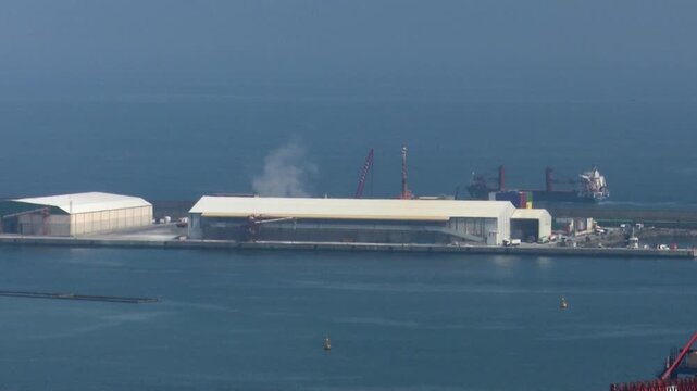 Aerial view of industrial port with large warehouses cranes cargo ship