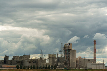 Obraz premium Cement factory. Piles of sand and crushed stone on the factory grounds. Large machinery working at the factory.