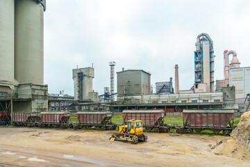 Obraz premium Cement factory. Piles of sand and crushed stone on the factory grounds. Large machinery working at the factory.
