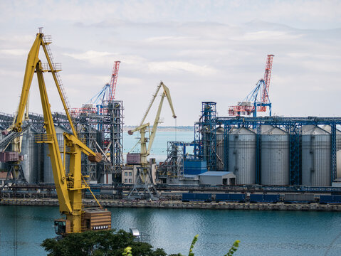 Industrial grain terminal at Odesa port, Ukraine. Cargo cranes and metal silos by the sea