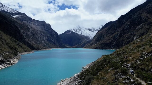 Huaraz, Peru: Forward footage of famous laguna paron in Caraz, Huaraz region, Peru. Surrounded by mountain range and with cloudy dramatic sky, showing cordillera blanca in the background