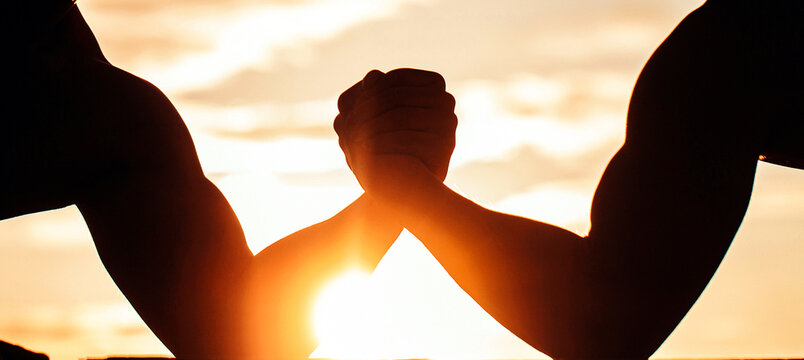 Arm wrestling. Sunset, sunrise. Men measuring forces, arms Two men arm wrestling