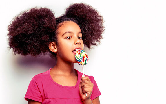 Girl smiling lollipop in hand on background. Girl afro, lollipops. Smile little african american girl eating lollipop