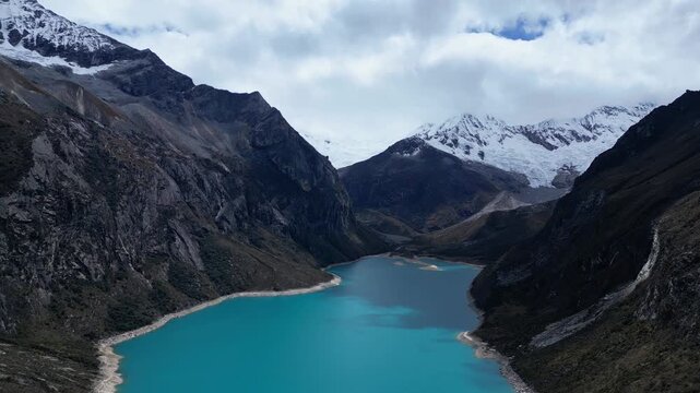 Huaraz, Peru: Forward footage of famous laguna paron in Caraz, Huaraz region, Peru. Surrounded by mountain range and with cloudy dramatic sky, showing cordillera blanca in the background