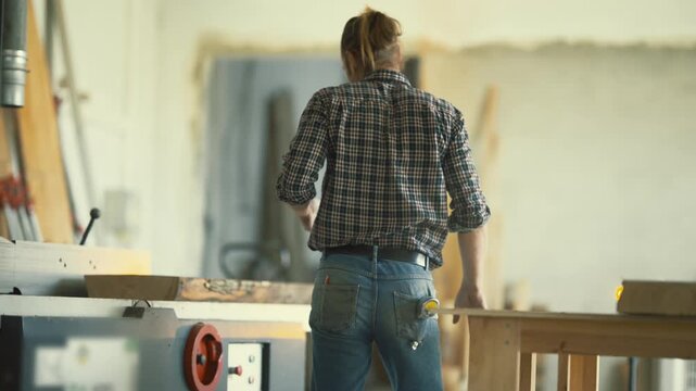 Carpenter working with a jointer plane machine in a workshop
