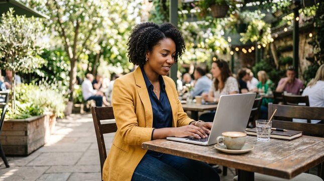  Young Black professional woman working on laptop at outdoor cafe