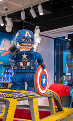 Obraz premium New york, usa august 19,2024. Captain america lego figure showcasing a red, white, and blue shield inside a busy lego store, featuring a brick built taxi