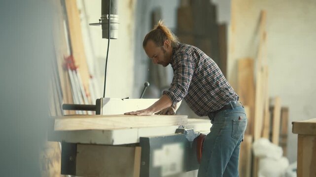 Professional carpenter planing wood board in workshop