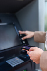 Fototapeta premium Close up of hand inserting bank card into ATM machine, modern banking transaction and financial technology concept