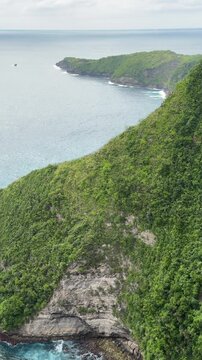 Vertical video capturing a sweeping panoramic view of the iconic Kelingking Cliff, also known as the T‑Rex Head, on Nusa Penida, Indonesia.