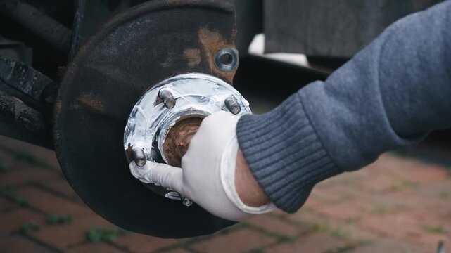 Spreading anti seize graphite grease across wheel hub contact surface during brake maintenance. Protective coating reducing corrosion buildup and preventing future rotor seizure. DIY automotive repair