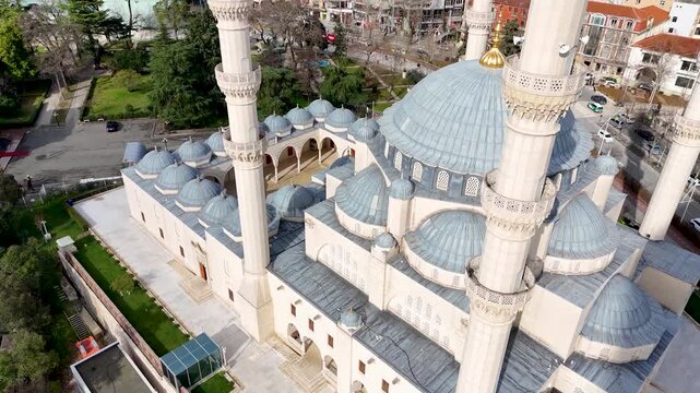 Aerial circles counterclockwise in a high-angle close-up around the grand central dome, golden finial, and towering white minarets of Namazgah Mosque in Tirana, Albania