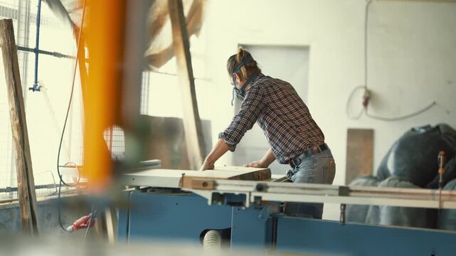 Male carpenter planing wood board in workshop