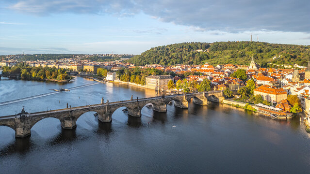 Charles Bridge stretches over the Vltava River in Prague, connecting the historic city with stunning views of the surrounding landscape and vibrant architecture during golden hour.