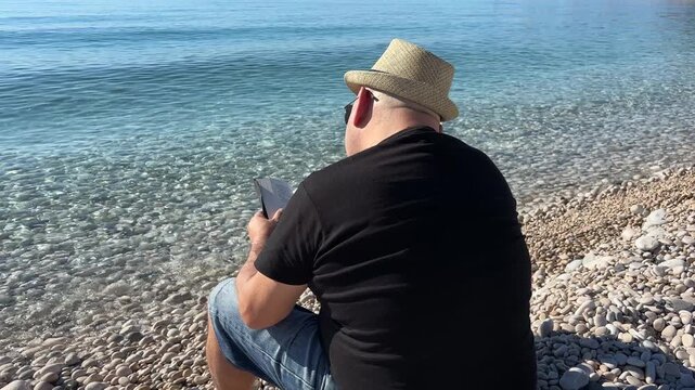 Hombre leyendo relajado junto al mar tranquilo