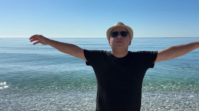 Hombre respirando profundo con brazos alzados junto al mar