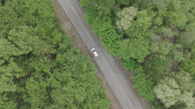 Aerial view of scenic landscape of driving a car in a deserted area through a tropical forest