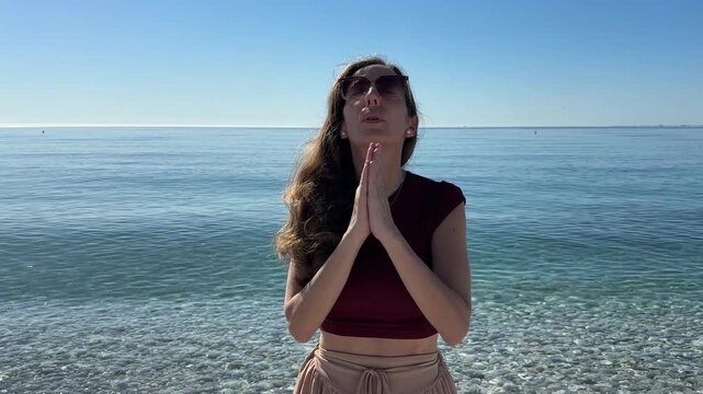 Mujer respirando profundo con brazos alzados junto al mar