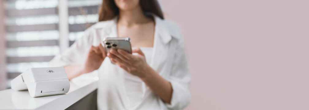A woman pays at a cafe with a plastic card using a payment terminal. Small business settlements, accounting, and taxes for cash register and electronic payments. banner copy space