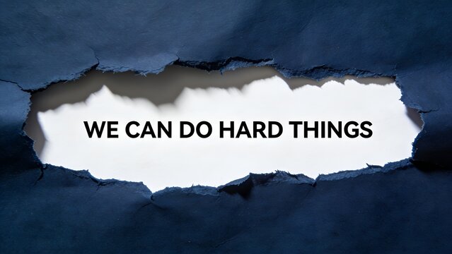 An inspirational photograph of the text we can do hard things displayed inside a large jagged hole torn through a dark blue piece of textured paper