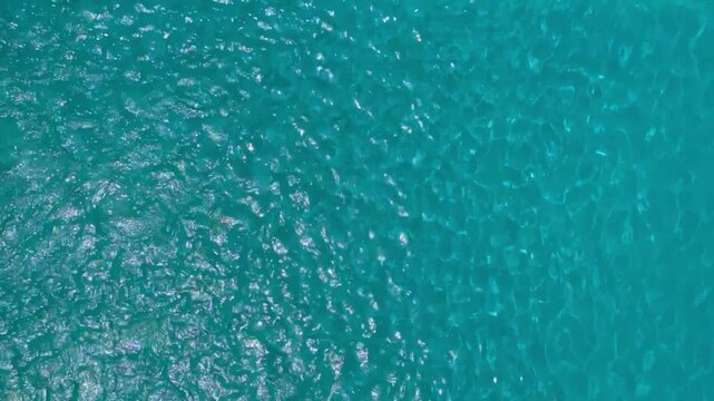Crystal clear turquoise swimming pool water surface with bright sunlight ripples