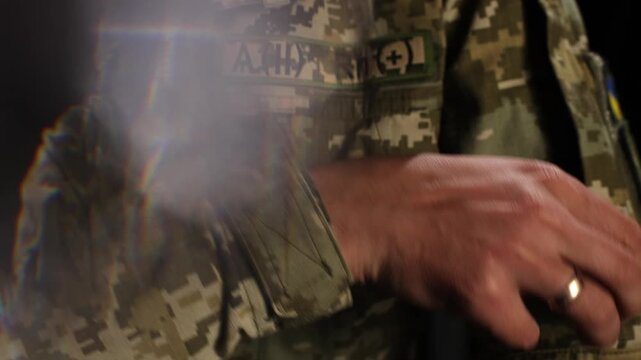 A symbolic close-up of a Ukrainian soldier in camouflage uniform retrieving a tactical patch with traditional Ukrainian embroidery (vyshyvanka) from a pocket. Represents national identity, patriotism,