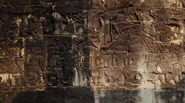 Ancient stone carvings depicting battle and procession scenes near Angkor wat, Cambodia