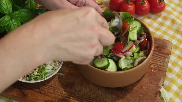 Woman cooking vegetable salad. Preparing diet summer food. Hands using spoon to mix salad ingredients in plate. 