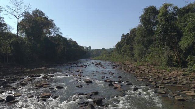 Aerial shot moving backwards at a low altitude and tilting down while flying over tad pha suam falls.