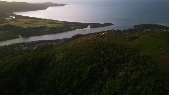 Aerial dolly of hikers and campers on Mount Lantad summit overlooking Bato River and coastal landscape in Catanduanes, Philippines