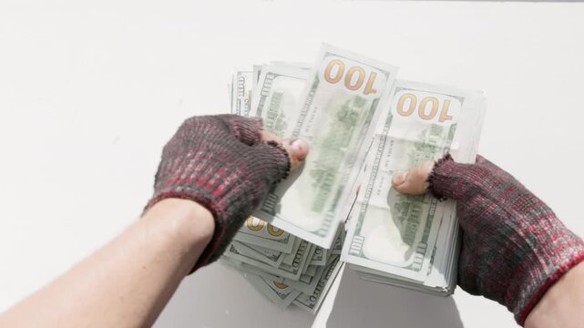 Fingerless gloves hands counting large stack of US dollar fiat money on white table